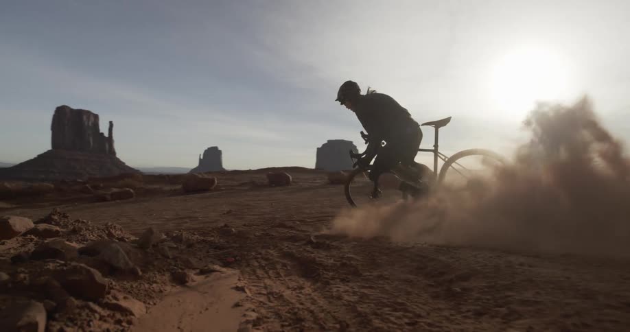 A bicyclist slides around a dusty corner in the desert