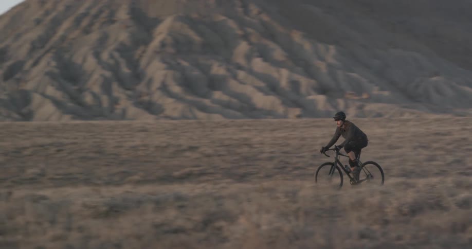 A cyclist riding a bicycle through desert canyon terrain