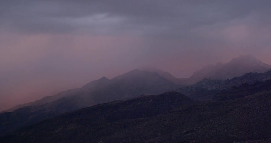 Clouds blowing over a mountain range at sunset