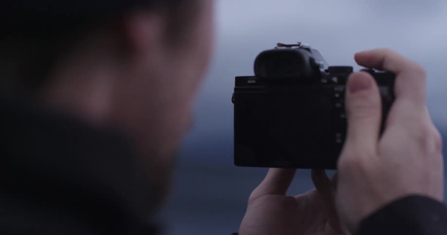 A man taking a photo with a digital camera before checking it on the cameras screen