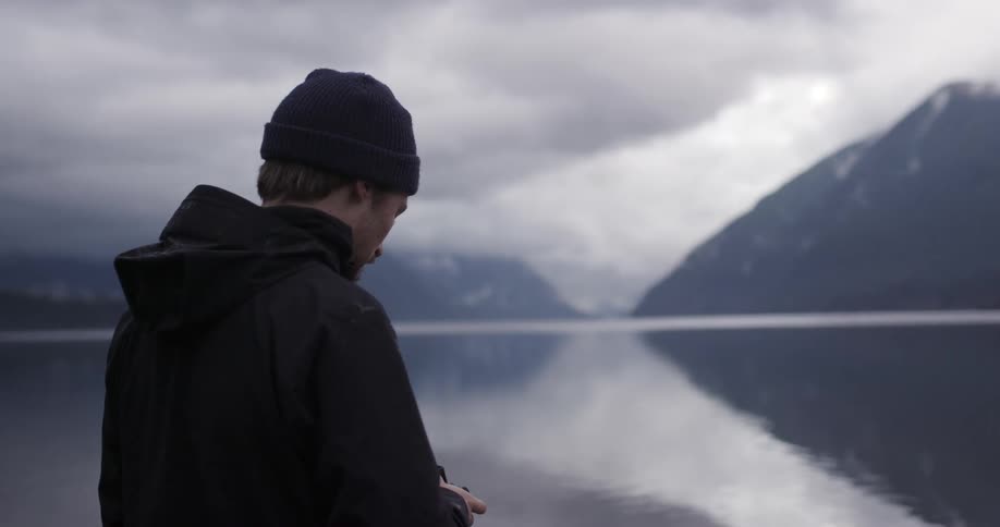 A man stands in front of a lake