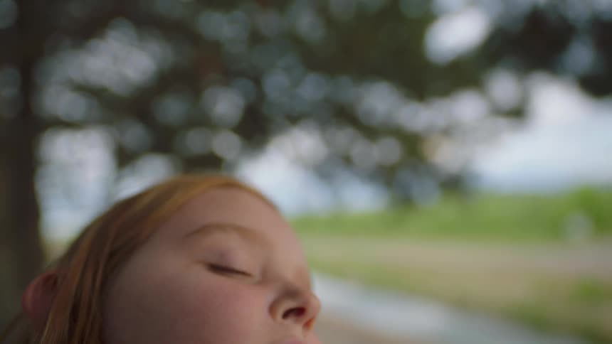 A girl sleeping while sitting outdoors on a sunny day