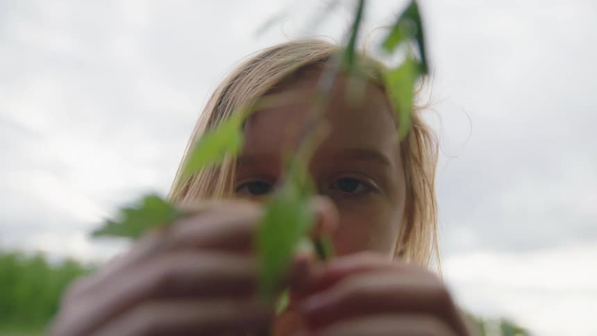 A young girl picks something off a plant