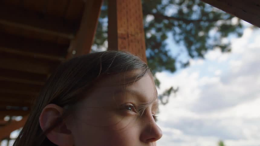 Girl occupying porch near post looks outward