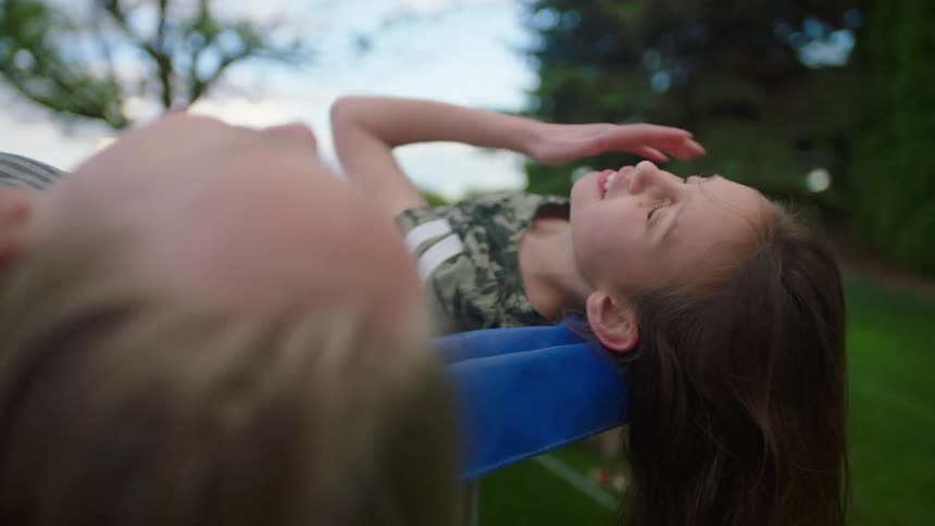 Two young girls lie outside and laugh and talk