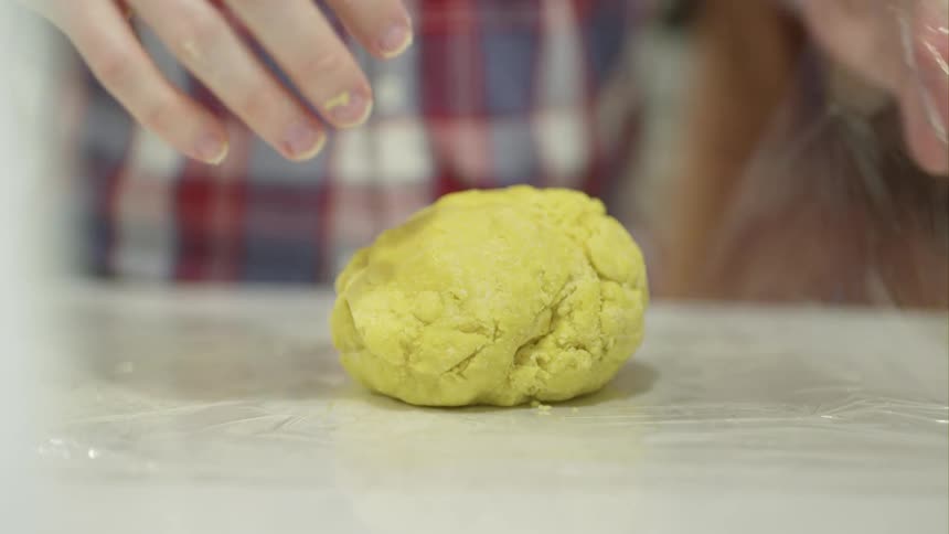 A man is wrapping dough in plastic wrap