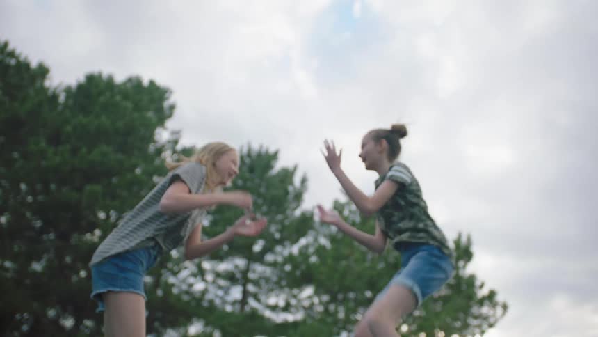 Girls playing and jumping on a trampoline outdoors