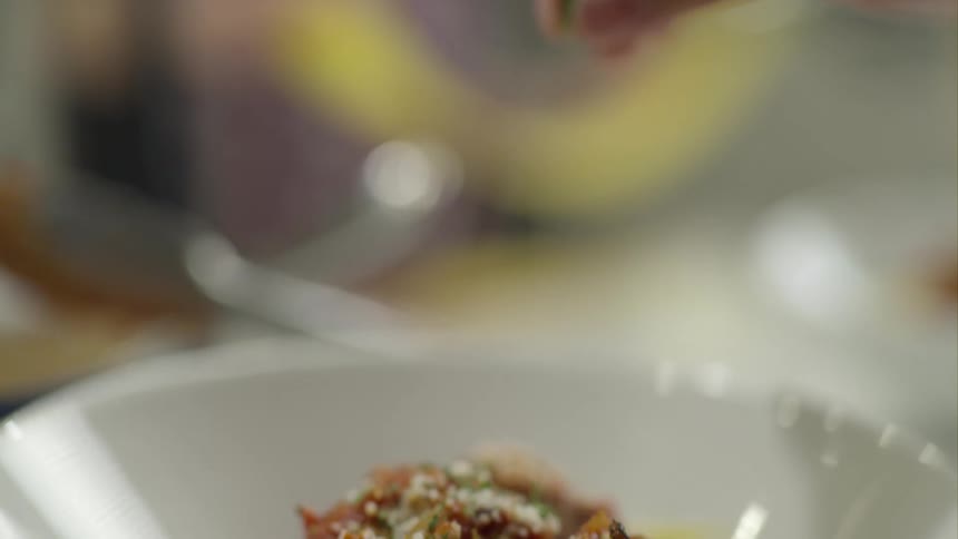Herbs being sprinkled over a gourmet meal