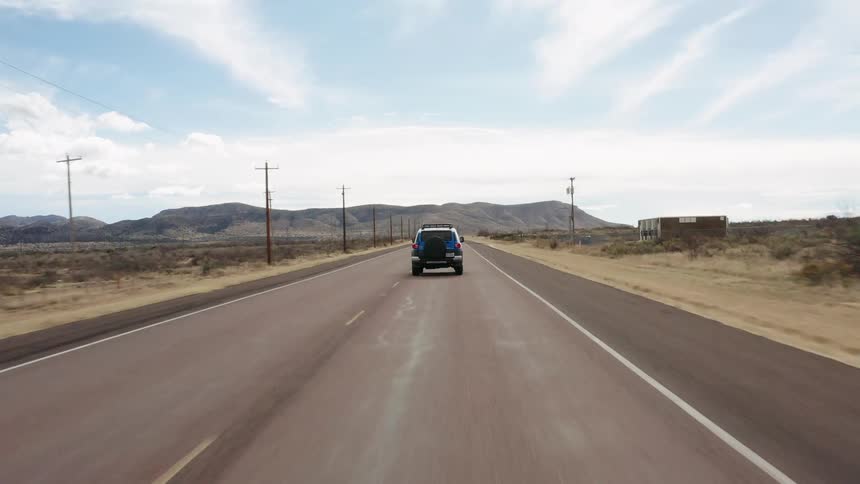 Car driving on a rural road through the desert at day