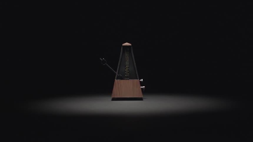A metronome goes back and forth under a light