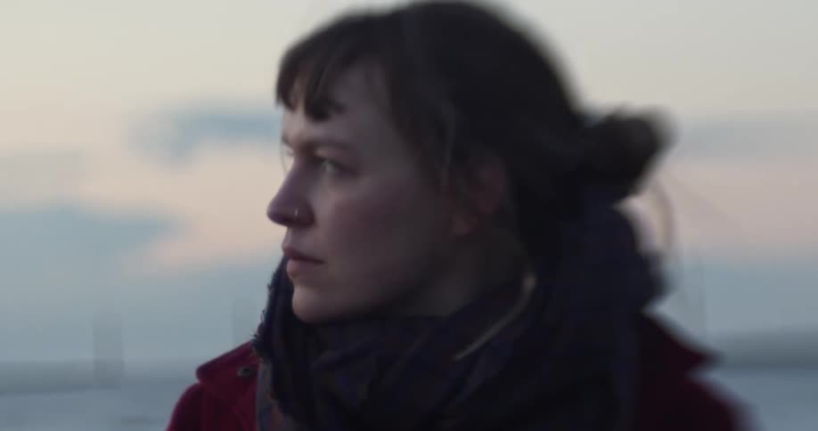 A woman standing near the coast with the sky in the background