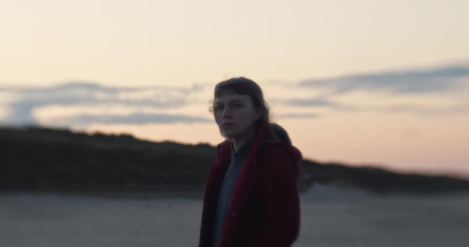 Woman stands on the sand beach at sunset