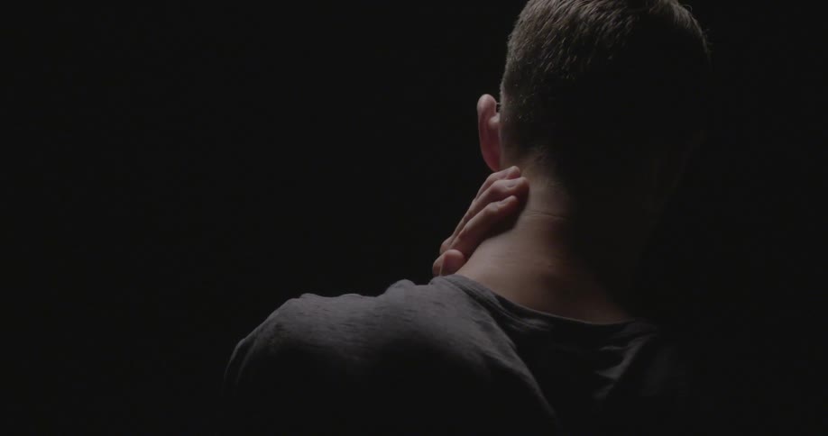 A man stands against a dark background