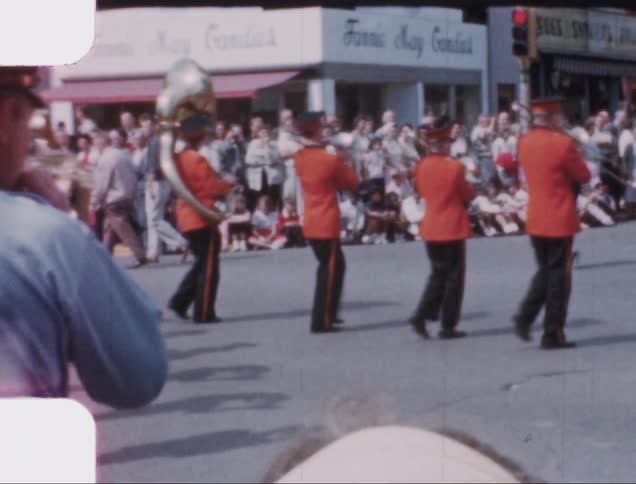 Vintage footage of a marching band in a parade on the streets of a small town