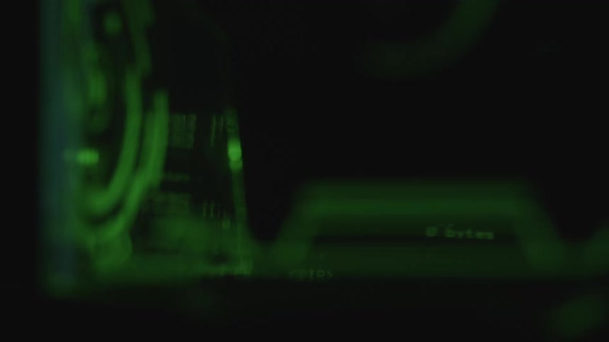 Green text and lines of code scroll on a black screen