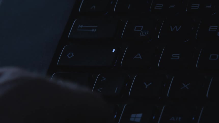 Person types on keyboard with led lit
