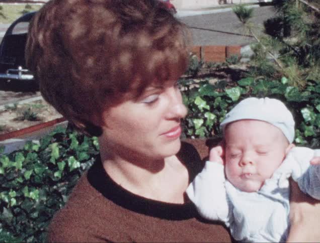 A mother holds her son while standing outdoors