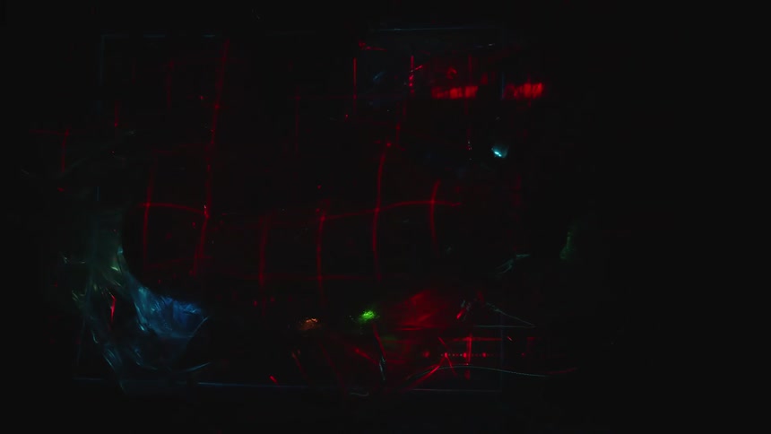 Naked skin shows through plastic enveloping person amid cables flickering lights and light beams