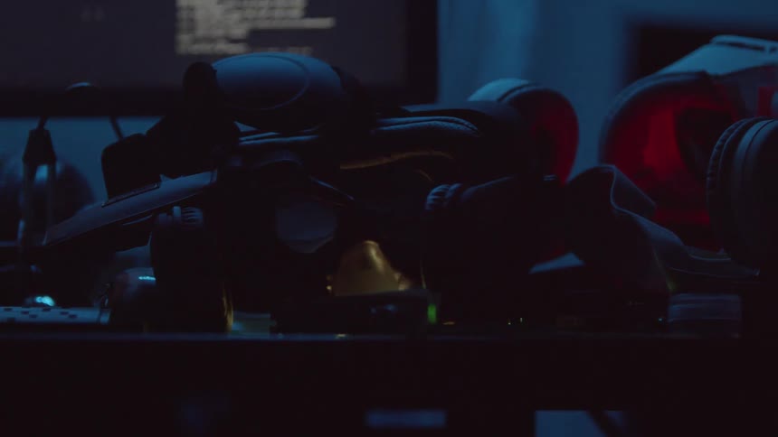 Gear sits piled on a table as a computer monitor displays code