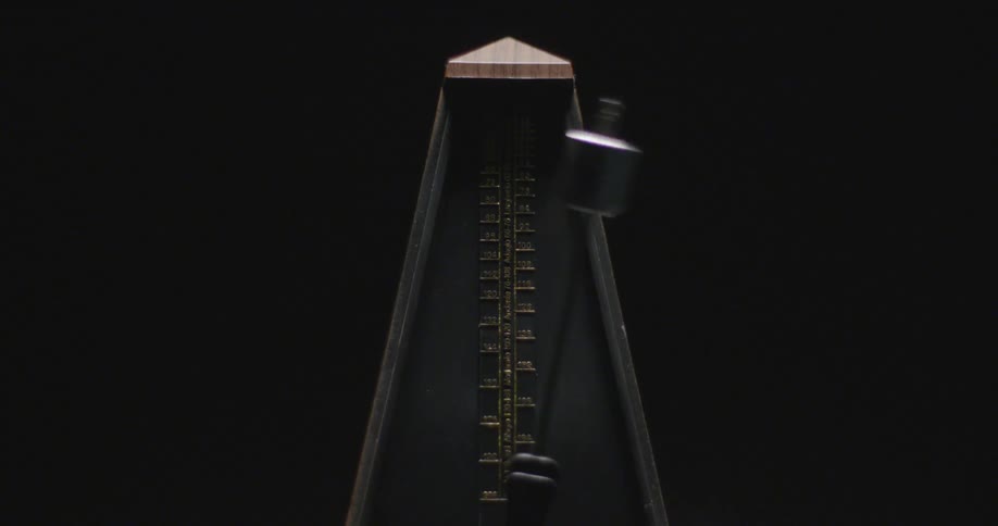 A metronome ticks in a dark room