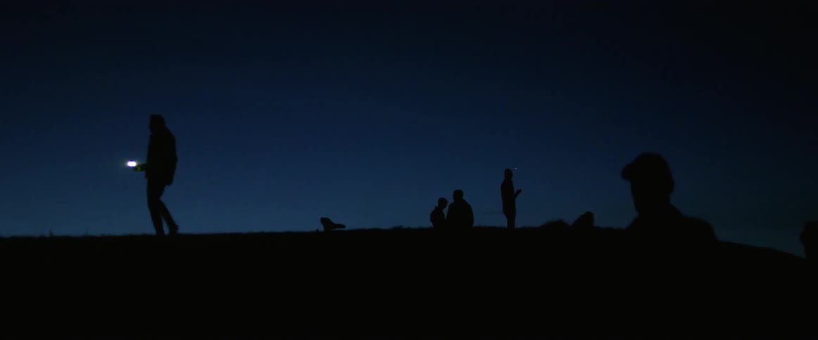 Several people walk around outdoors at night
