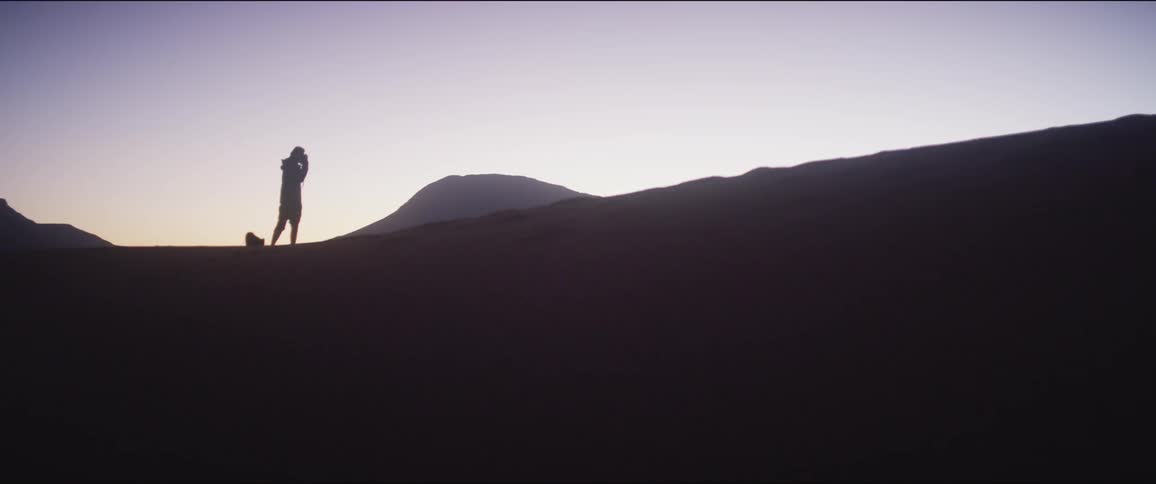 Silhouette of a man takes a picture in the desert