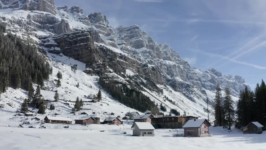 A small village covered in snow sits in a mountain valley