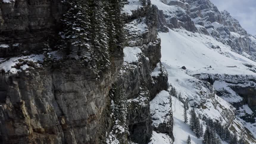 The sheer cliffs of a snow covered mountain during the day