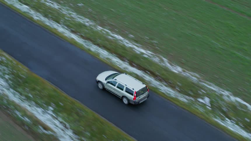 Aerial view of a car driving on a road in the countryside
