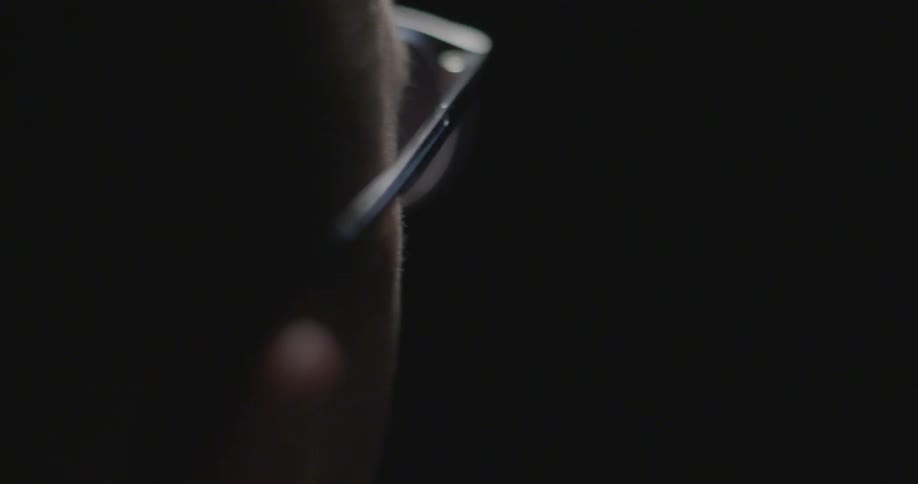 Man in glasses looking around in dark room