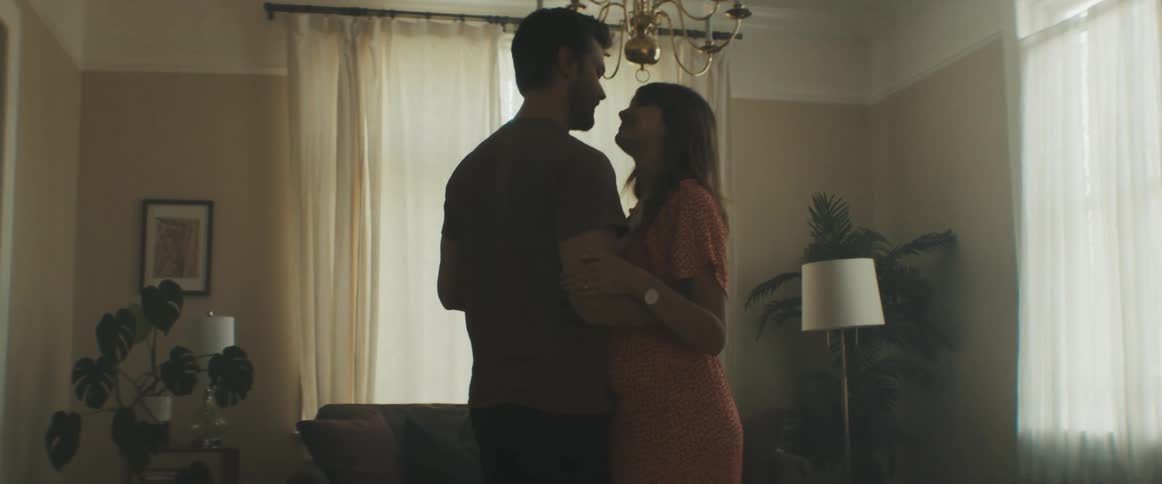 Husband and pregnant wife dance together in the living room