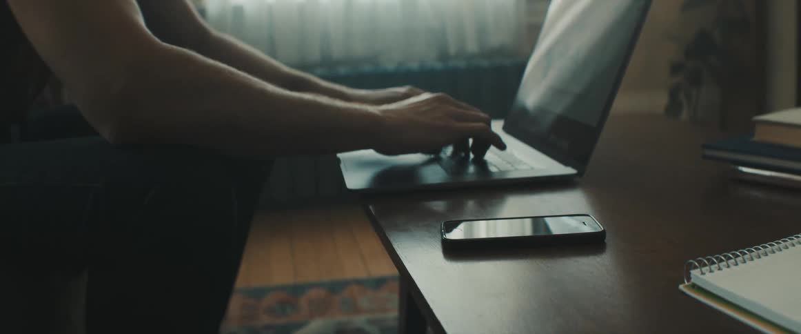 A man sits in his living room and types on his laptop