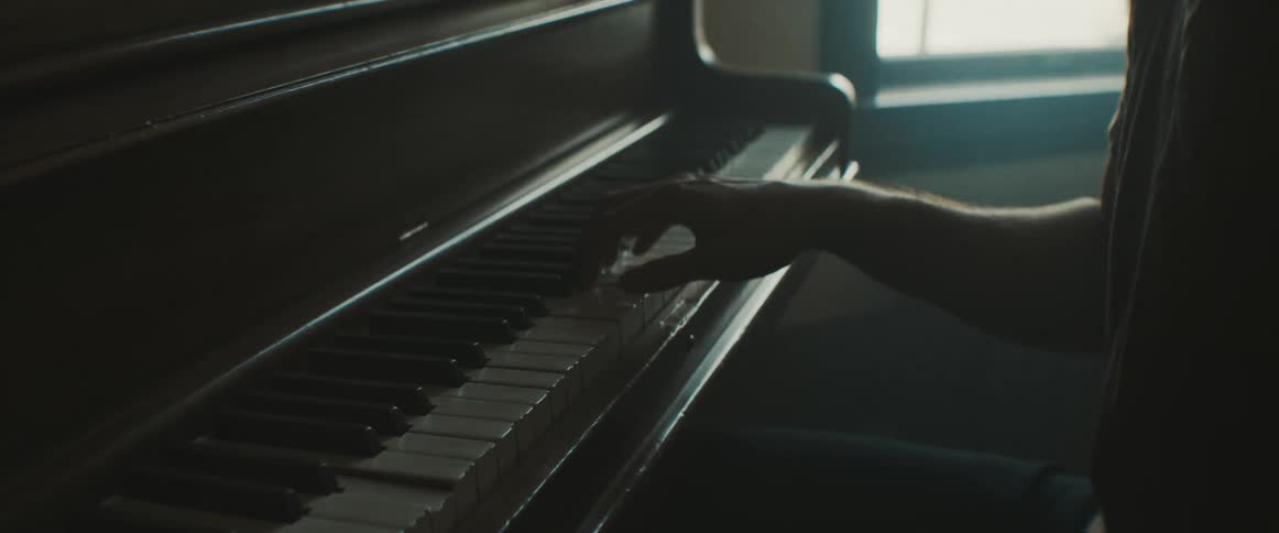 A man plays the piano with one hand