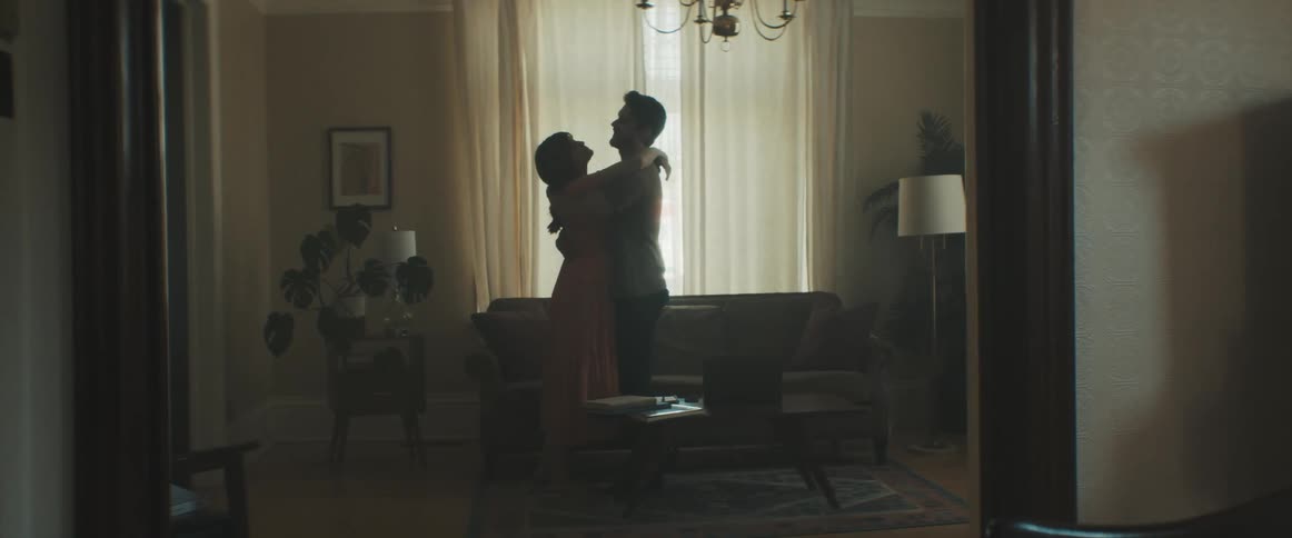Couple in front of a window wrap their arms around each other