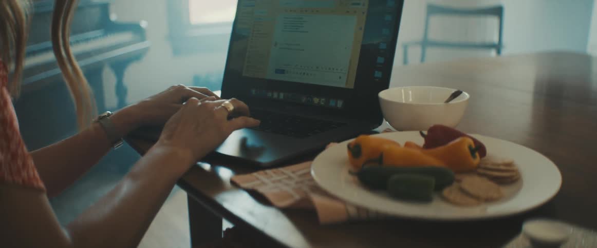 Woman eats some food and uses her laptop at home
