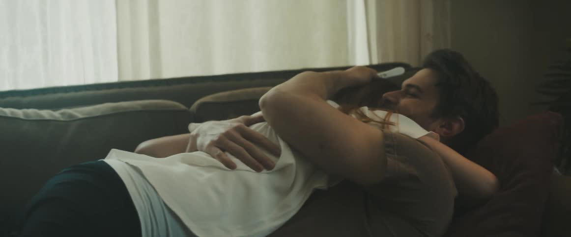 Young couple playfully hug each other in a couch on the living room