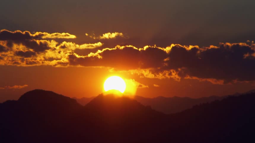The sun rises over a silhouette of a mountain range