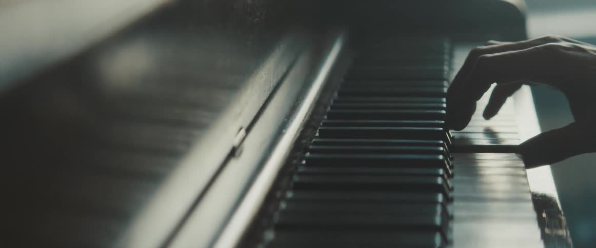 Hands pressing the keys of a piano indoors during the day