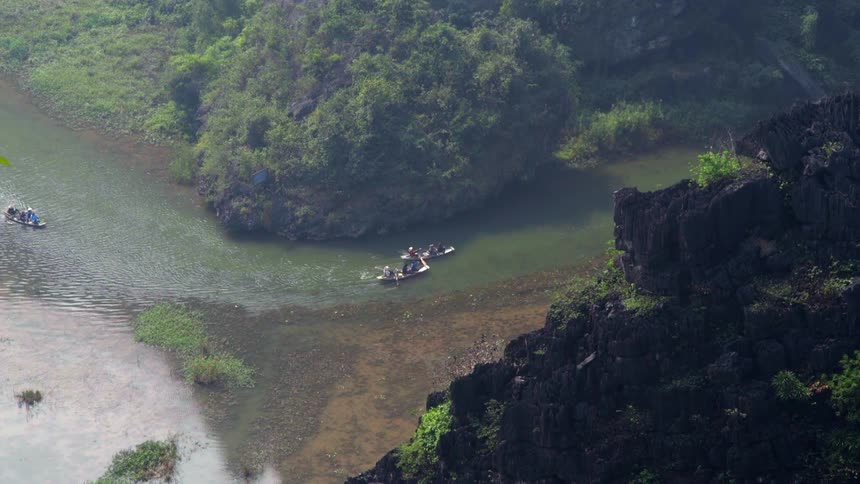 People paddle canoes down the river near the trees