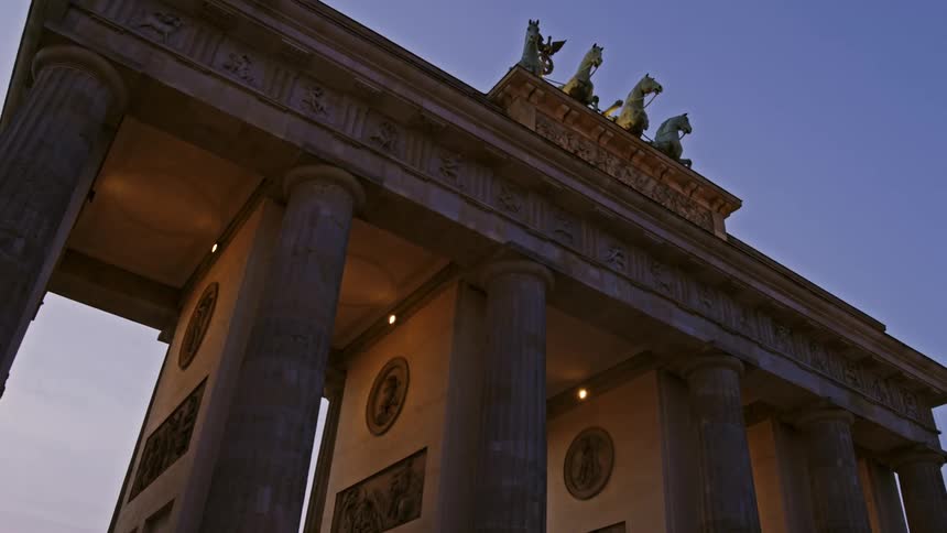 An ancient arch with horse statues and round reliefs inside
