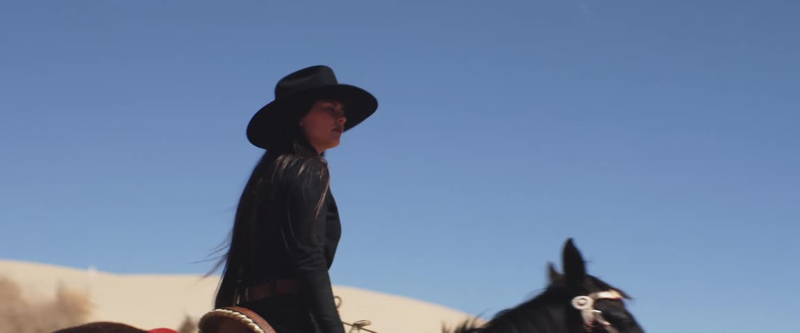 Woman rides a dark horse in the desert