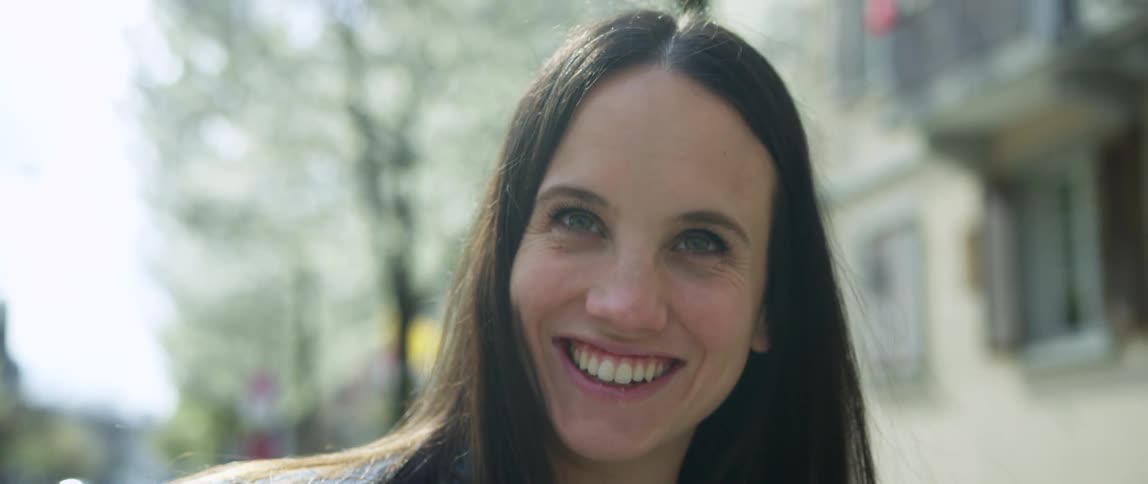A woman is standing outdoors and smiling