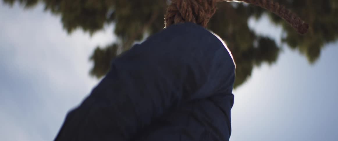 A man with a noose around his neck looks around