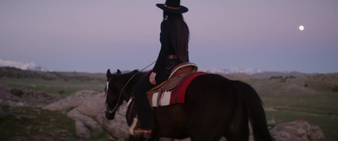 Woman wearing cowboy hat slowly rides a horse