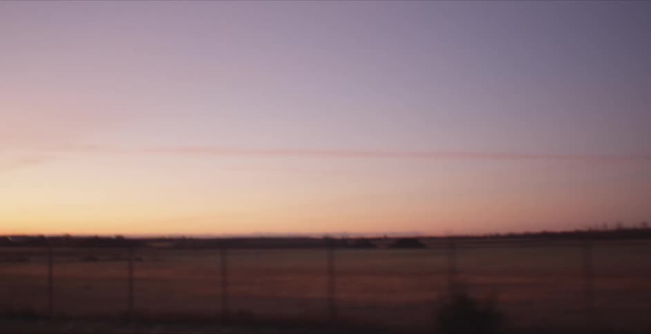 The sun sets past the open land
