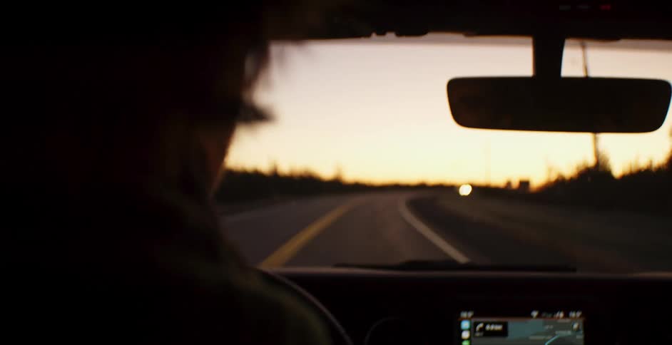 Man drives on a highway at sunset
