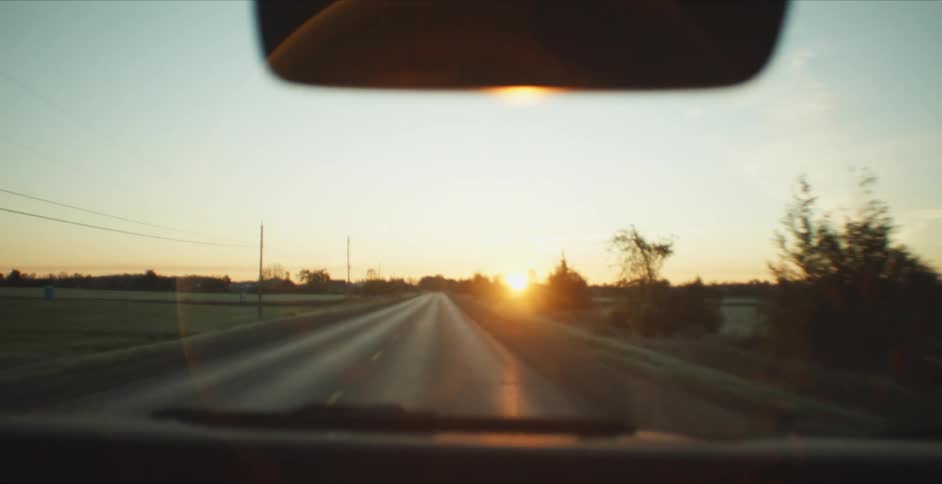 Vehicle drives along road in the countryside at sunset