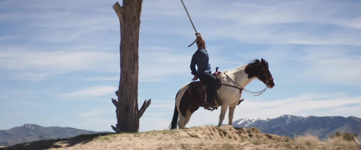 A man sits on his horse with his head in a noose