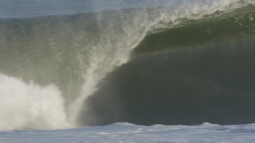 Sunlight reflects off of a large cresting wave