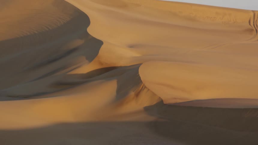Footprints dot ridge in desert among sand dunes